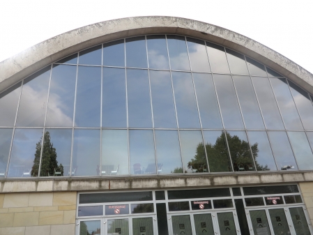 die markante Form der Weser-Ems Halle,  nin den Scheiben spiegeln sich Wolken und Pflanzen 