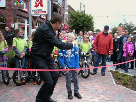 Bürgermeister Matthias Huber gibt dem 10jährigen Paul Ripken die Schere um das Band durchzuschneiden